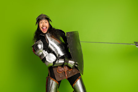 Knight in medieval armor displaying a humorous expression against a vibrant green backdropの写真素材