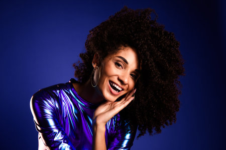 Glamorous young woman in a stylish purple dress enjoying a lively disco party with a charming smile on a vibrant violet backgroundの写真素材