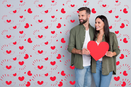 Portrait of attractive tender cheerful couple hugging holding heart card copy blank space isolated over grey pastel color backgroundの写真素材