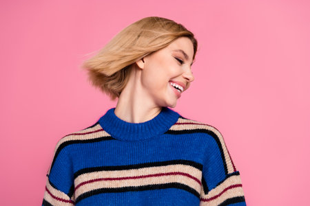 Portrait of a young woman smiling in a striped sweater against a pink backgroundの写真素材