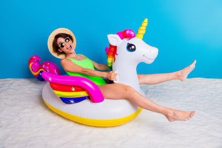 Young woman enjoying summer vibes with a unicorn pool float on sandの写真素材