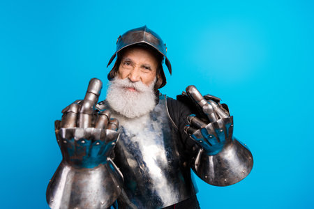 Bearded senior man in armor displaying confidence against a blue backgroundの写真素材