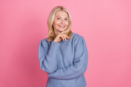Photo portrait of attractive senior woman thinking touch chin dressed stylish blue knitted clothes isolated on pink color backgroundの写真素材