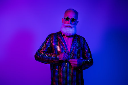 Photo of attractive cool senior guy wear shiny jacket star glasses praparing party emtpy space isolated violet neon color backgroundの写真素材