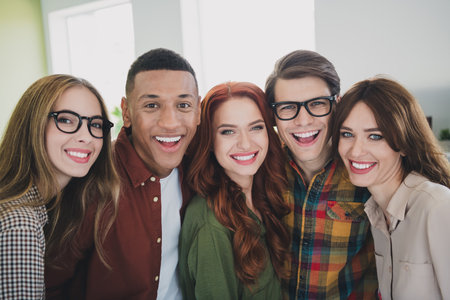 Portrait of young successful colleagues toothy smile hug workplace business center office indoorsの写真素材