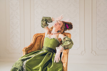 Elegant woman in a vintage green dress posing indoors in a styled historical setting for a modern...