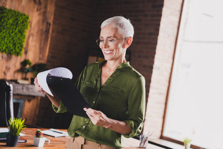 Photo of charming attractive lady dressed shirt eyewear hold cv resume document workplace workstation loft interior indoorsの写真素材