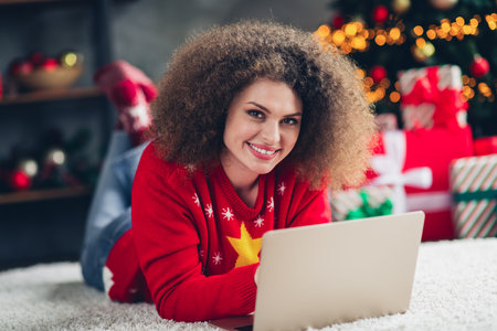 Photo of pretty cheerful woman lying carpet choose buy gifts online order christmas holidays atmosphere decorations indoorsの写真素材