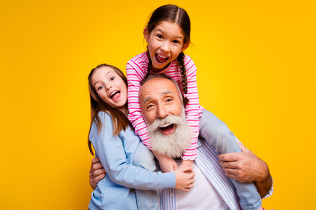 Happy family generation bonding with grandfather and grandchildren against a bright yellow backgroundの写真素材