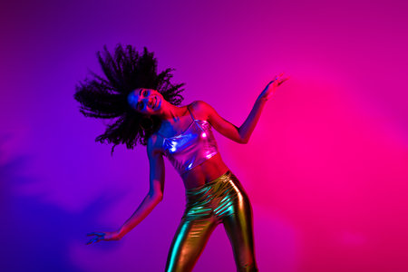 Vibrant young woman dancing with glowing neon colors in a colorful night ambiance