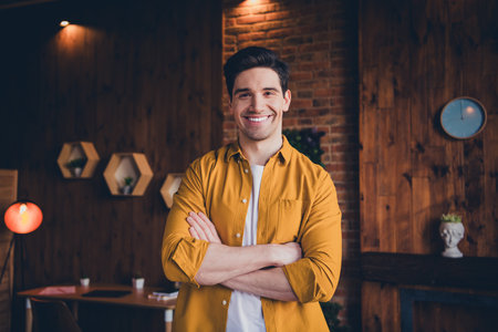 Young man smiling in stylish shirt inside a cozy loft living room with natural daylightの写真素材