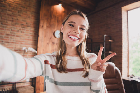 Charming young woman in casual sweater enjoying a relaxing day at homeの写真素材