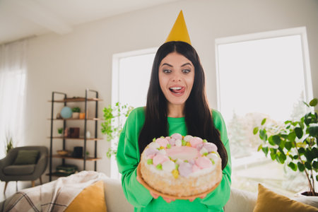 Young woman celebrating a special occasion while holding a beautiful cake with pink decorations
