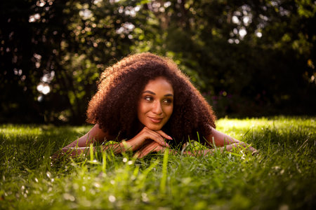 Pretty happy lovely lady lying green lawn sunny summer day weather photo session sunlight outdoorsの写真素材