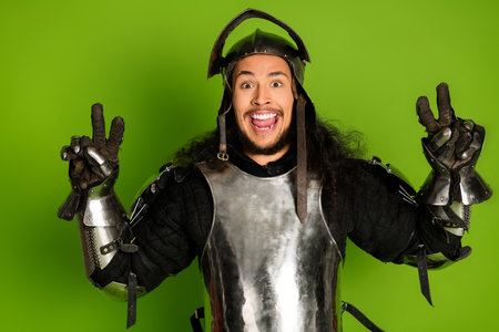 Funny young man in medieval knight armor posing with a green backgroundの写真素材
