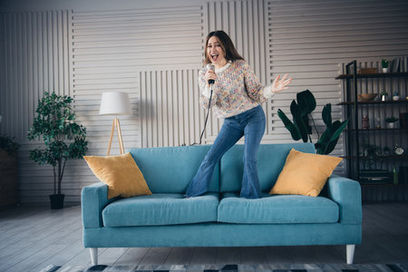 Woman singing confidently on couch inside a modern living roomの写真素材