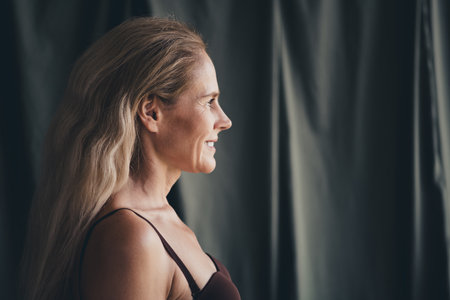 Confident mature woman embracing natural beauty in a studio profile shotの写真素材