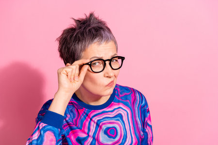 Photo portrait of attractive senior woman skeptical look empty space dressed blue colorful clothes isolated on pink color backgroundの写真素材