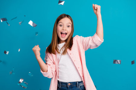Preteen Girl Celebrating Joyfully Against a Blue Background Cheerfullyの写真素材