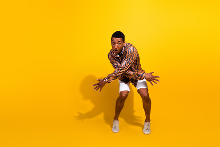 Stylish young man in trendy patterned shirt posing cheerfully against bright yellow background