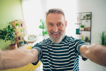 Happy bearded man enjoying a relaxing day at home in a sunlit living room