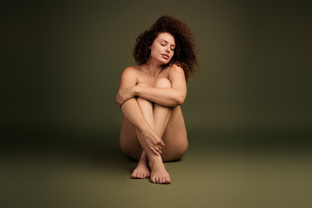 Portrait of a young confident woman sitting gracefully with a serene expression, embracing natural beautyの写真素材