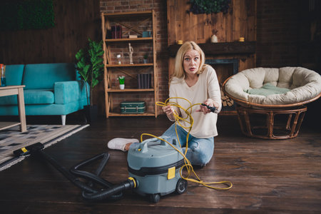 Photo of doubtful uncertain woman dressed white shirt preparing doing weekend cleaning indoors house apartment roomの写真素材