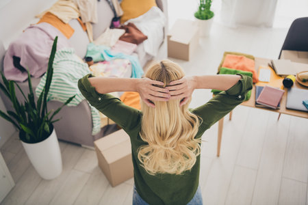 Rear view photo of stressed shocked woman relocation rent move new apartment flat mess clothes living room indoorsの写真素材