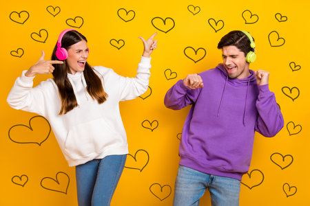 Photo of overjoyed millennial lady handsome guy enjoy mp3 melody pastime isolated on yellow color backgroundの写真素材