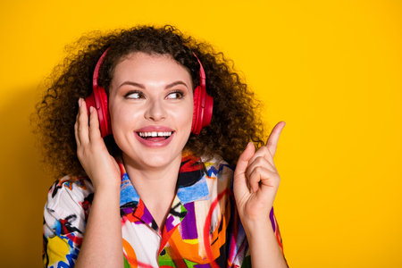 Photo of lovely young lady headphones point look empty space dressed stylish colorful print garment...