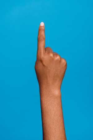 Cropped closed up vertical photo of girl hand finger direct up empty space one isolated on blue color backgroundの写真素材