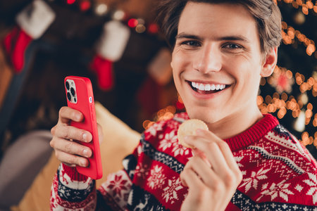Photo of cheerful positive guy dressed ornament pullover enjoying x-mas eve texting modern gadget...