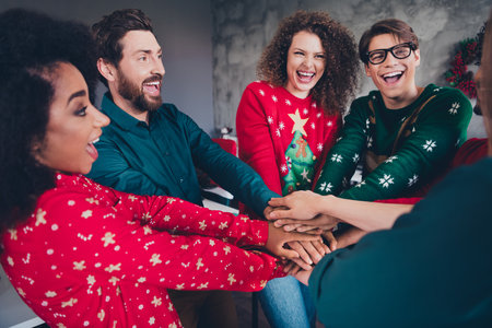 Photo of cheerful young people colleagues hold hands circle cozy christmas party decor spacious office indoorsの写真素材