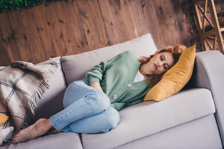 Photo of tired upset lady wear green cardigan lying sofe feeling pain indoors room home house