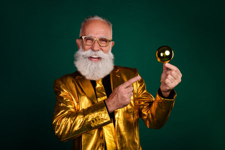 Charismatic elderly gentleman in golden suit celebrates holiday with festive cheer and glamourの写真素材