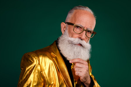 Elegant elderly man in a golden suit posing with charisma on green background, embodying retro...