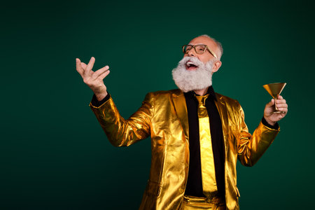Joyful elderly gentleman in elegant golden suit celebrating a glamorous eventの写真素材