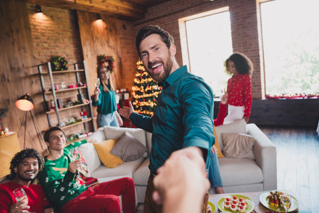 Photo of attractive young people hold hand follow friend handsome man new year decoration interior celebrate home party apartmentの写真素材