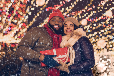 Photo of two peaceful people hold x-mas noel giftbox congratulating evening lights outsideの写真素材