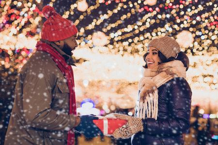 Profile side view portrait of attractive cheerful couple family strolling spending eve evening giving sharing gifts city urban outdoorsの写真素材