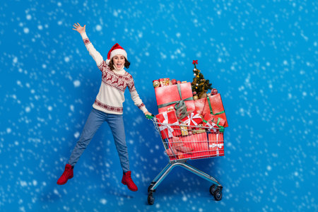 Full length photo of overjoyed lady rejoice hold supermarket pushcart full boxes giftboxes isolated on blue color backgroundの写真素材