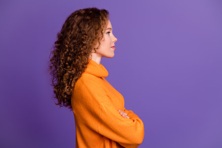 Photo of charming lovely girl wear trendy orange clothes crossed arms empty space isolated on purple color backgroundの写真素材