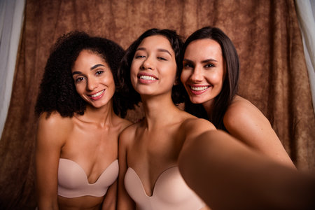 Selfie of three body positive model support self acceptance wear comfy lingerie isolated on brown color backgroundの写真素材