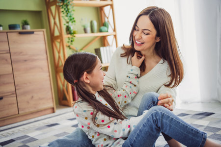 Smiling young mother and daughter sharing a joyful moment at home on a sunny day