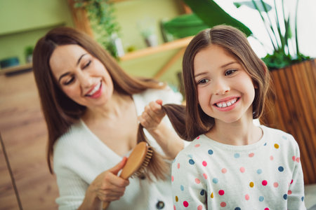 Joyful young mother and daughter bonding at home on a bright spring day, sharing laughter and loveの写真素材