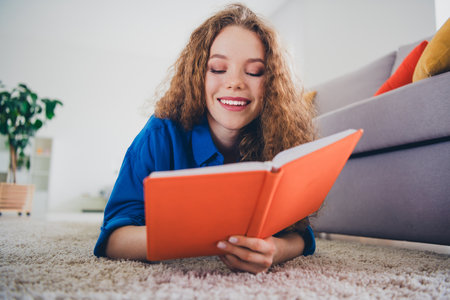 Photo of lovely charming girl wearing blue clothes lying floor writing diary cozy weekend day indoors living room apartment flatの写真素材