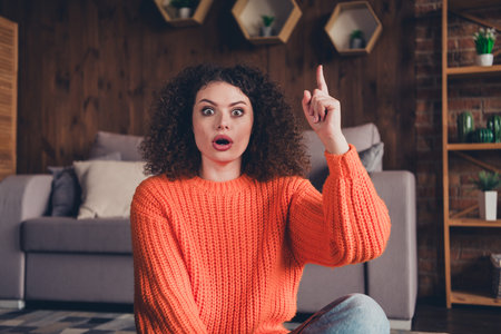 Portrait of nice young girl open mouth point finger wear orange sweater modern loft interior flat indoorsの写真素材