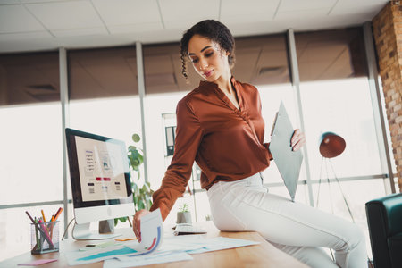 Confident young businesswoman multitasking effectively in a modern office environmentの写真素材
