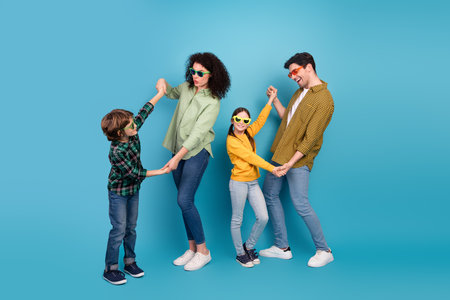 Happy family wearing sunglasses, playfully bonding against a blue background promoting joy and...