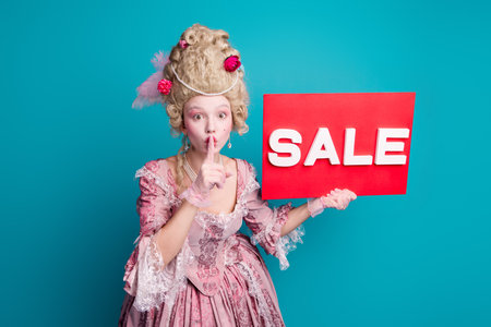 Portrait of young princess girl shh gesture poster wear vintage dress isolated on turquoise color backgroundの写真素材